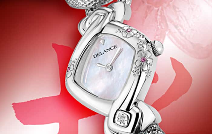 Kanon acier : Montre en acier sertie de 3 fleurs gravées avec un cœur de saphir rose, cadran nacre blanche, cabochon en acier avec un diamant à 6h, bracelet en gourmette